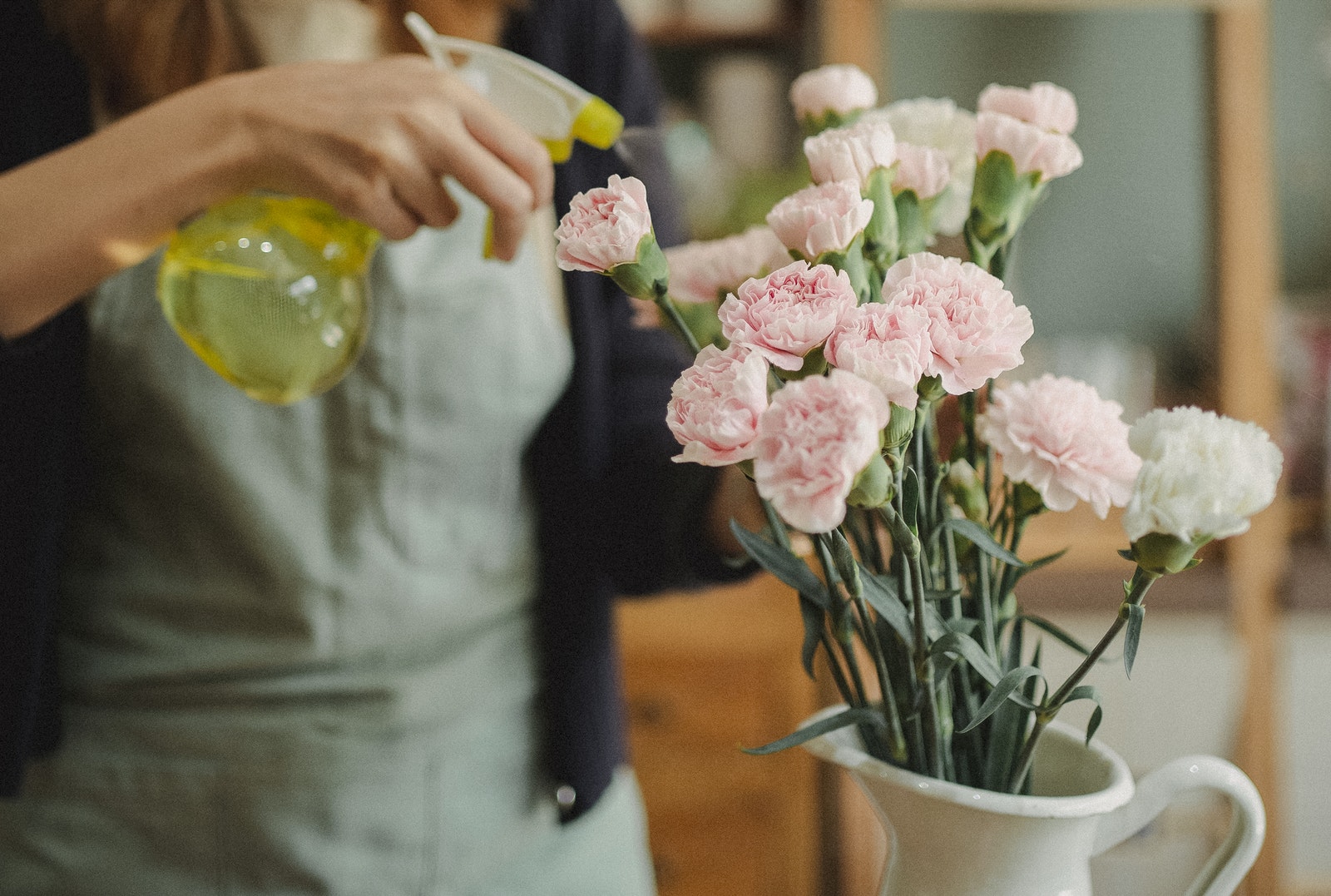 Crop woman spraying bouquet of flowers