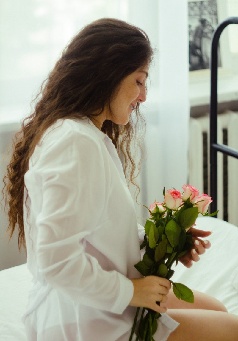 Frau mit Rosen sitzt im Bett