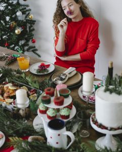 Frau sitz am dekorierten Tisch und Weihnachtsbaum