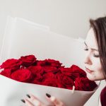 Frau hält Kopf an rote Rosen