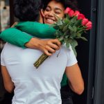 Frau umarmt Mann und freut sich über Rosen