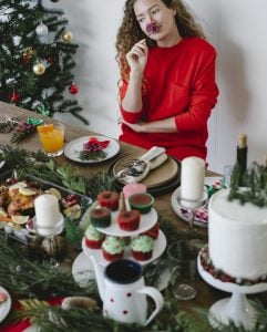 Frau sitz am dekorierten Tisch und Weihnachtsbaum
