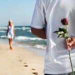 Mann schenkt Frau eine Rosen am Strand