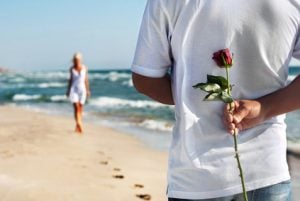 Mann schenkt Frau eine Rosen am Strand